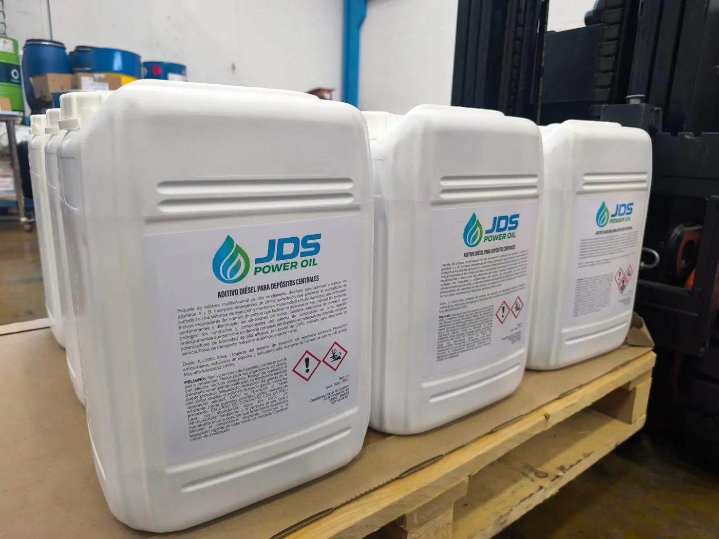 Garrafas de 20 litros de aditivo diésel JDS Power Oil sobre un palet en almacén.